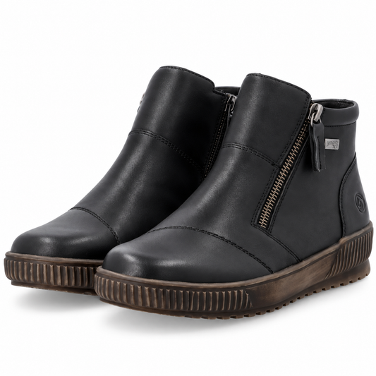 A pair of black leather ankle boots with side zippers, featuring a brown ribbed sole, shown on a white background.